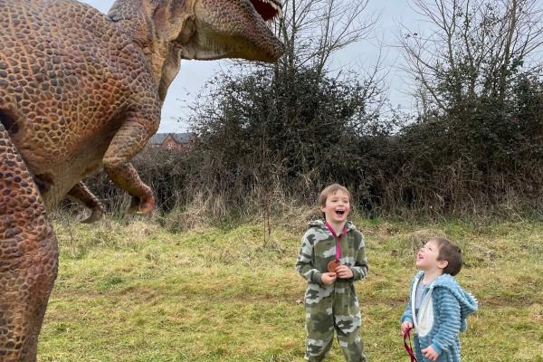 Dinosaur entertaining two small children